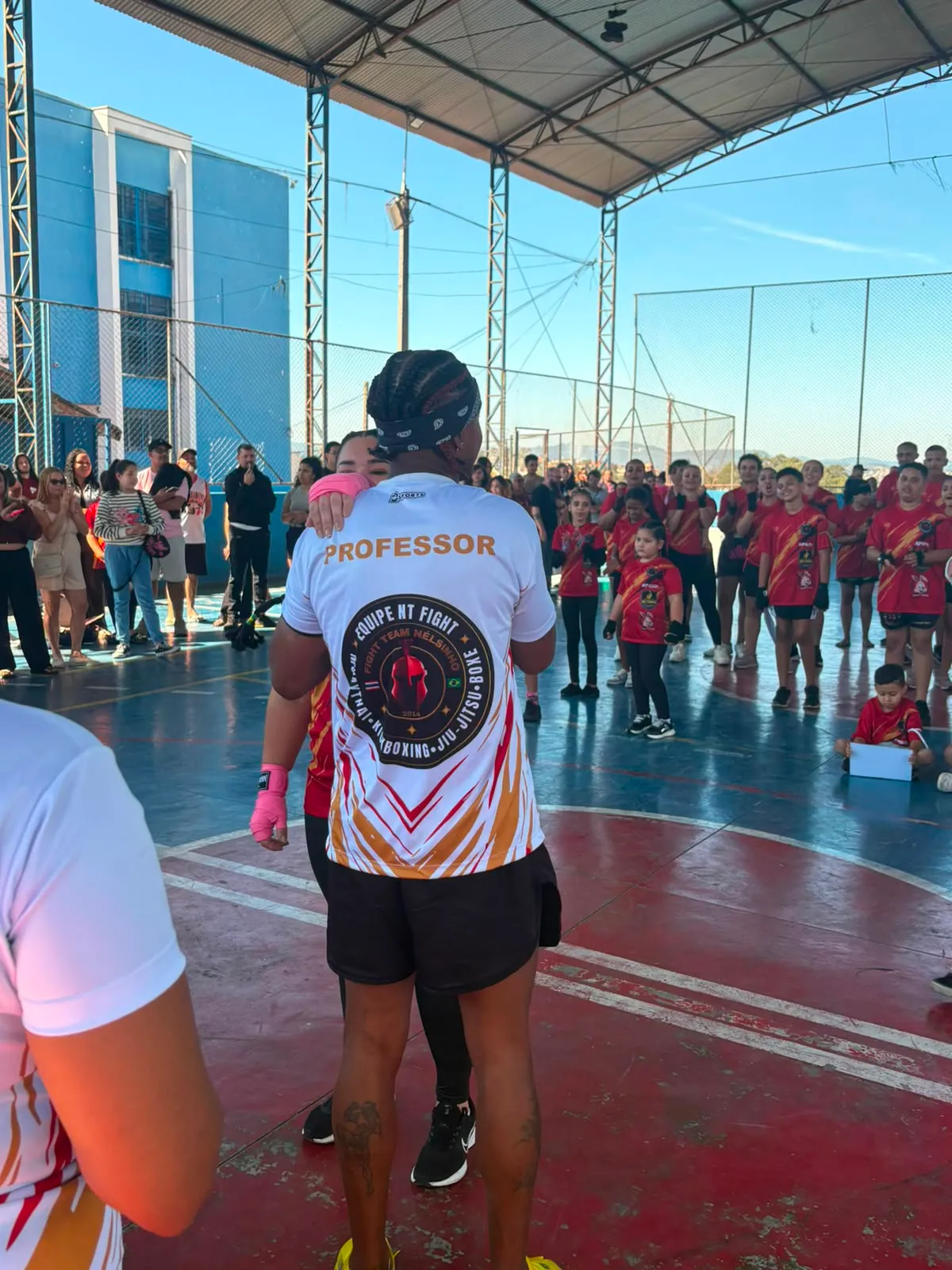 Prof. Nélsinho de frente para os alunos reunidos na quadra, no início da cerimônia de graduação de julho de 2026
