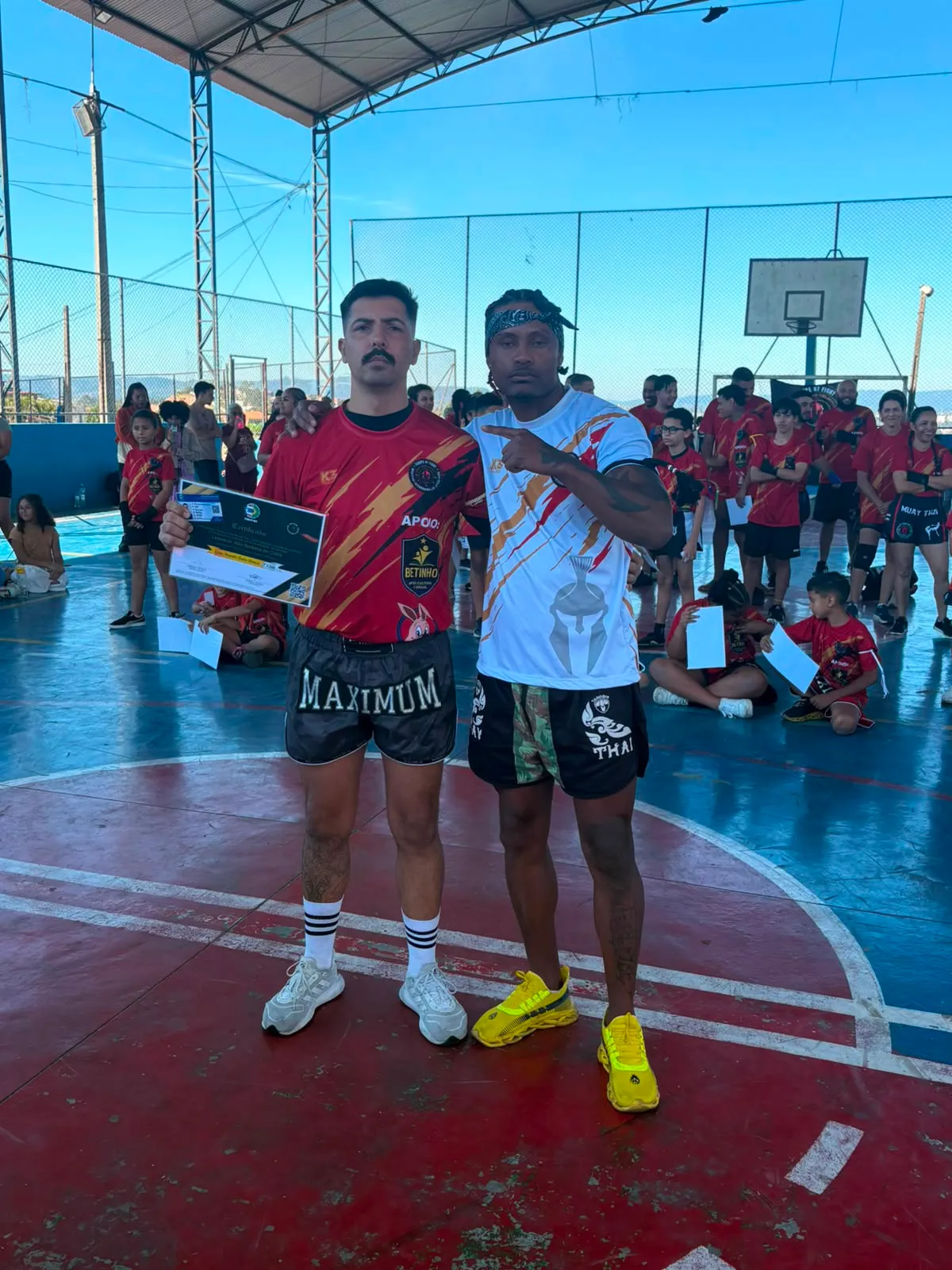 Aluno da Equipe NT Fight com o certificado de graduação ao lado do Prof. Nélsinho, na cerimônia de julho de 2026